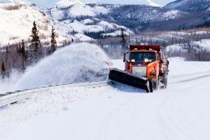 Snow plough clearing road in winter storm blizzard
